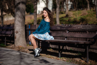 Portrait of woman sitting on bench in park