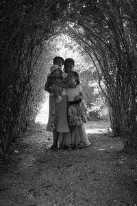 Full length of happy mother with children standing amidst trees