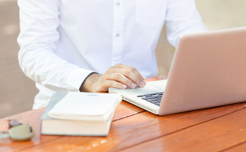 Midsection of man using laptop on table