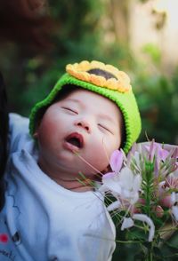Cute baby girl sleeping by blooming flowers in park