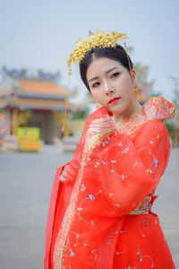 Portrait of young woman in traditional clothing standing at shrine