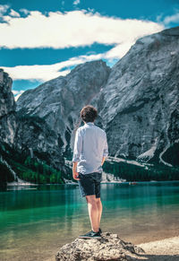 Rear view of man standing on rock by lake