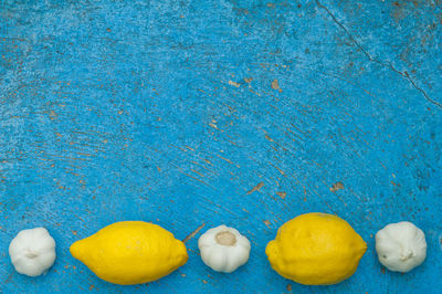 High angle view of garlic and lemons on blue wooden table
