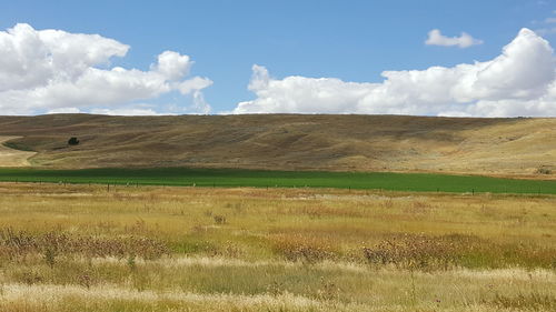 View of field against cloudy sky