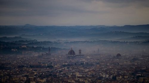 View of cityscape against cloudy sky