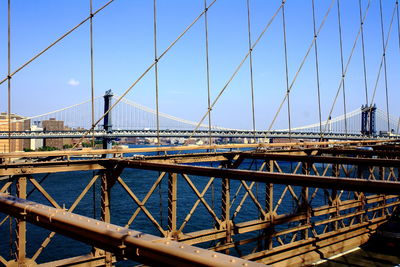 Suspension bridge in city against sky