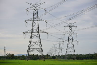 Low angle view of electricity pylon on field against sky