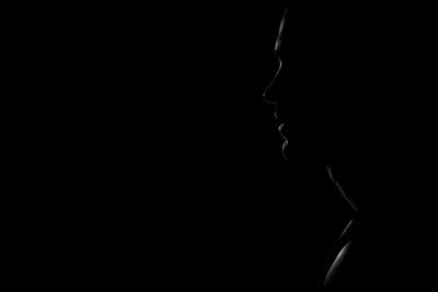 Close-up portrait of silhouette man against black background