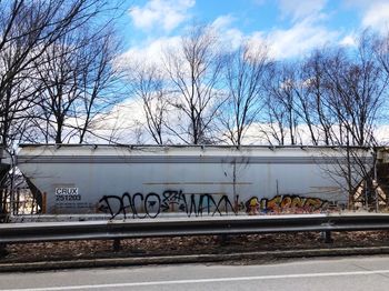 Graffiti on railroad tracks by bare trees against sky