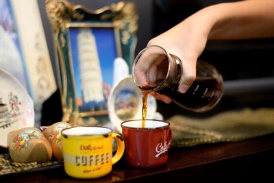 Close-up of hand pouring tea in cup