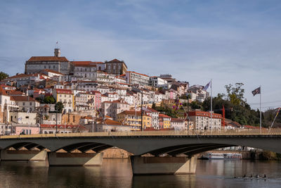 Bridge over river by buildings against sky in city