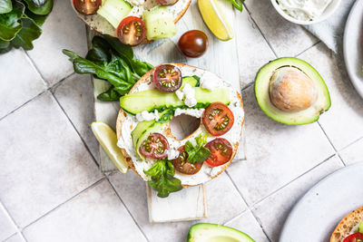 Bagels sandwich with cream cheese, cottage cheese, avocado, tomatoes, cucumbers and salad leaves