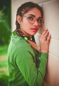 Side view portrait of young woman wearing eyeglasses by wall