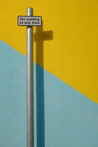 Close-up of sign on yellow and light blue wall
