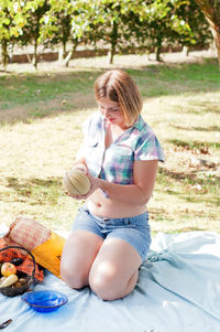 Young beautiful caucasian girl dressed in pin-up style on a picnic with fruits