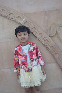 Portrait of smiling girl standing against wall