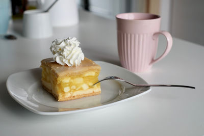 A piece of apple pie with cream and a cup of coffee. 