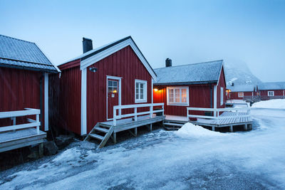 Houses by snow covered house against sky