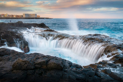 Scenic view of waterfall against sky