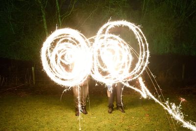 Full length of woman standing by illuminated heart shape at night