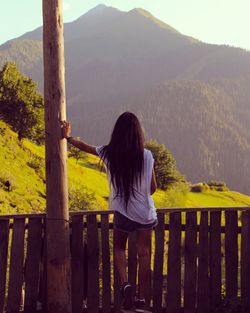 Rear view of woman standing by railing against mountains