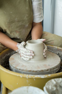 Midsection of woman making pottery in workshop