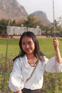 Portrait of smiling woman on swing in playground