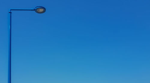 Low angle view of street light against blue sky