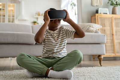 Young woman using phone while sitting on sofa at home