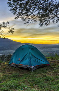 Tent on field against sky at sunset