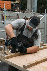 Builder with drill. man carpenter twists a screw into wooden plank with an electric screwdriver