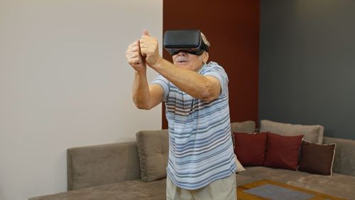 Senior man using virtual reality simulator at home