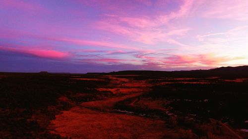 Scenic view of landscape against dramatic sky during sunset