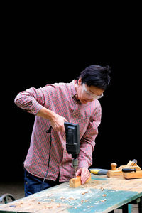 Man holding umbrella on table against black background