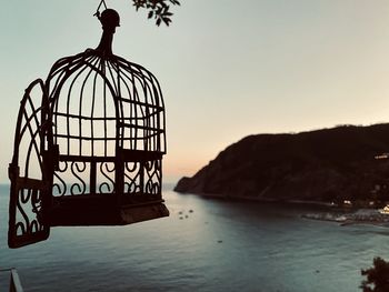 Silhouette metal by sea against clear sky during sunset