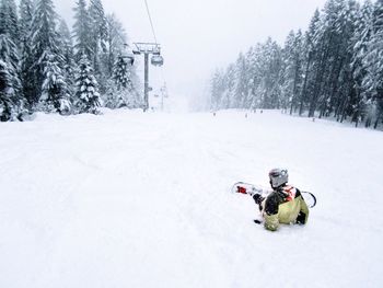 Person fallen on snowy field while skiing amidst trees