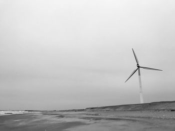 Wind turbines on beach against sky