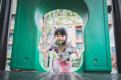 Cute smiling girl playing on slide in playground
