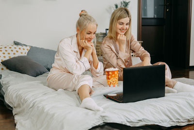 Woman using smart phone while sitting on bed