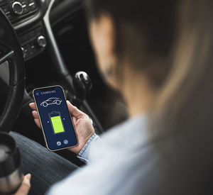 Mature woman using electric car charging app on smart phone