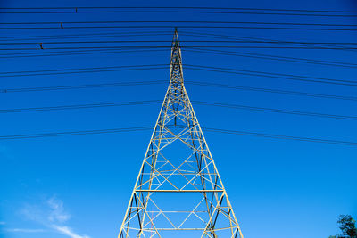 Low angle view of electricity pylon against blue sky