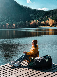 Man sitting by lake against trees