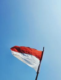 Low angle view of flag against clear blue sky