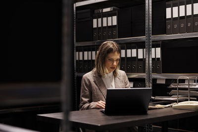 Young woman using laptop while sitting at office