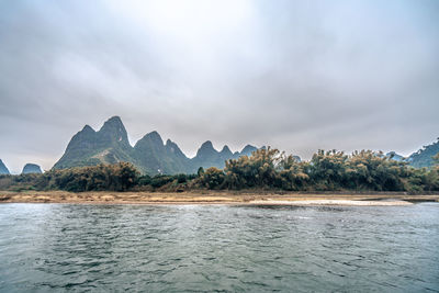 Scenic view of sea by mountains against sky