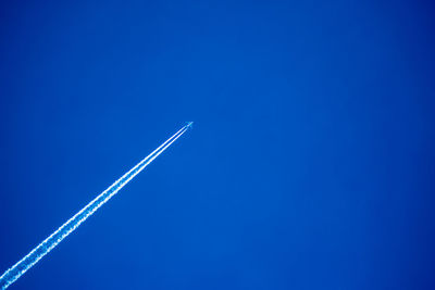 Low angle view of vapor trail against clear blue sky