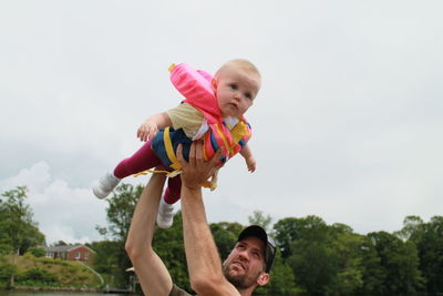 Side view of boy playing with arms raised standing against sky flying 