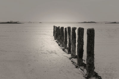 Wooden posts on beach against clear sky