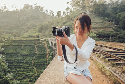 Full length of woman photographing against trees