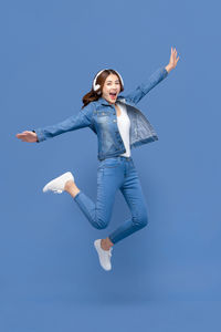 Young woman jumping against blue sky